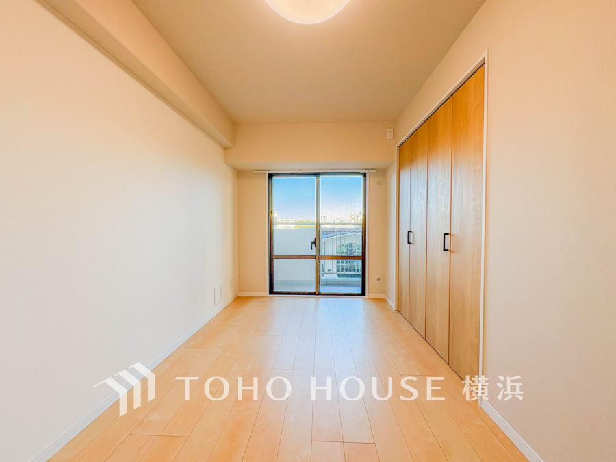 バルコニーから明るい自然光が差し込む洋室。大型クローゼット付きで収納も充実しています。
