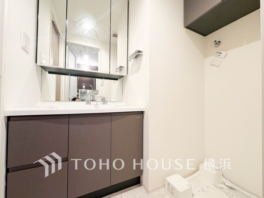 収納豊富な三面鏡洗面台と洗濯機置場を備えた清潔感あふれる洗面スペースです。