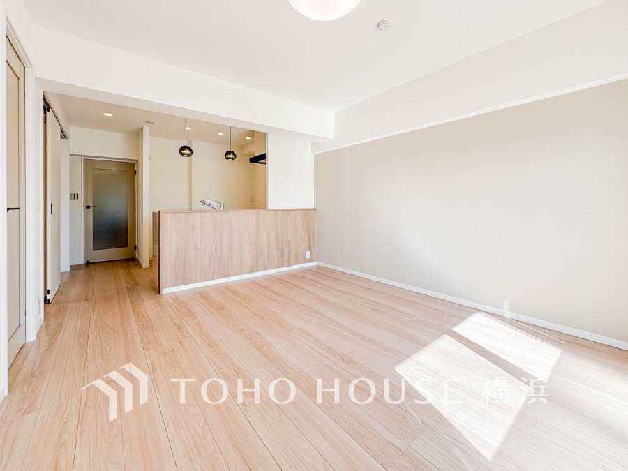 明るい自然光が差し込む、木目調の床とアクセントクロスが美しいリビングダイニングです。