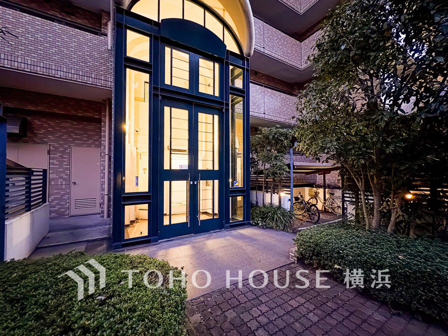 夜間も安心の明るいエントランス。緑豊かな植栽に囲まれ、静かな住環境が魅力のマンション入口です。