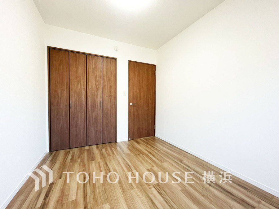 明るく清潔感のある洋室は、木目調の床と収納扉で温かみのある空間を演出しています。