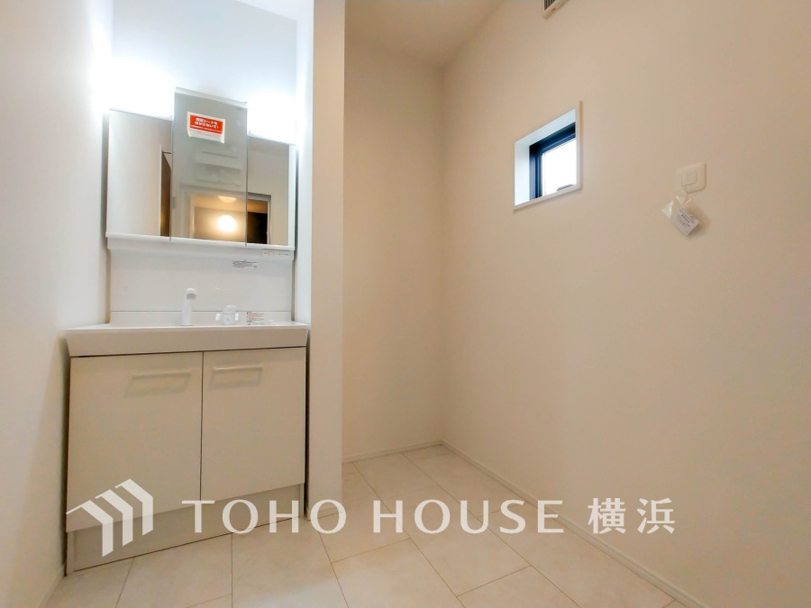 清潔感あふれる白基調の洗面スペース。小窓から自然光が差し込み、明るく快適な空間を演出します。