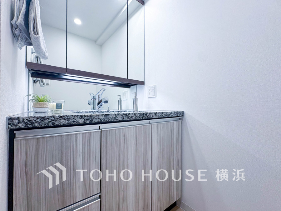 洗練された木目調キャビネットと大理石調カウンターの洗面スペース。収納も充実しています。