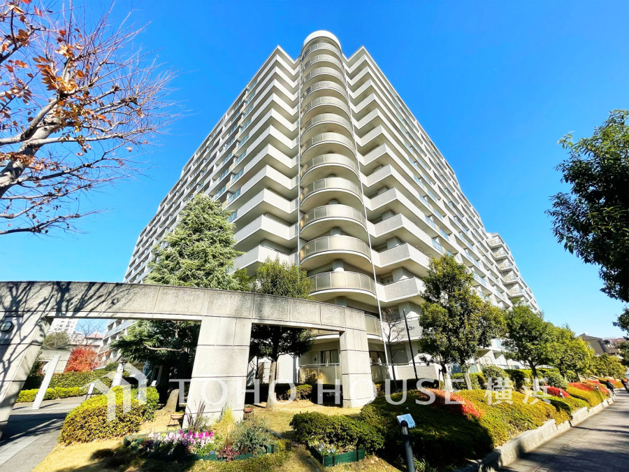 青空に映える高層マンション。緑豊かな植栽が彩る、快適で落ち着いた住環境が魅力です。