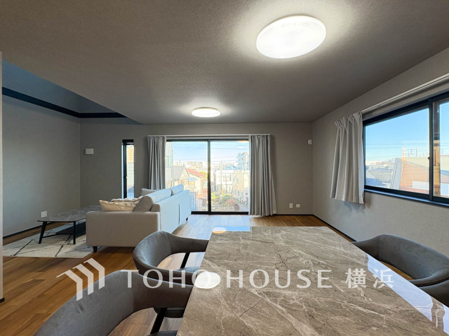 大きな窓から明るい光が差し込む、落ち着いた色調の広々としたリビングダイニング空間です。