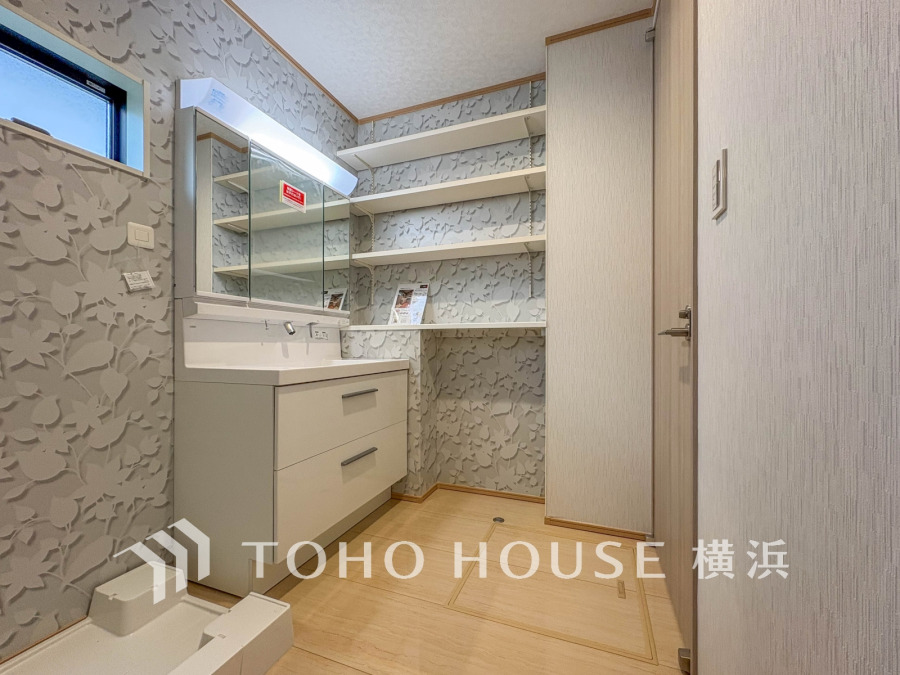 収納棚と洗面台が充実した、清潔感あふれる明るい洗面脱衣室です。小窓で自然光も取り入れます。