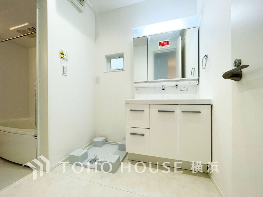 清潔感あふれるホワイト基調の洗面室。収納豊富な洗面台と洗濯機置場が使いやすく配置されています。
