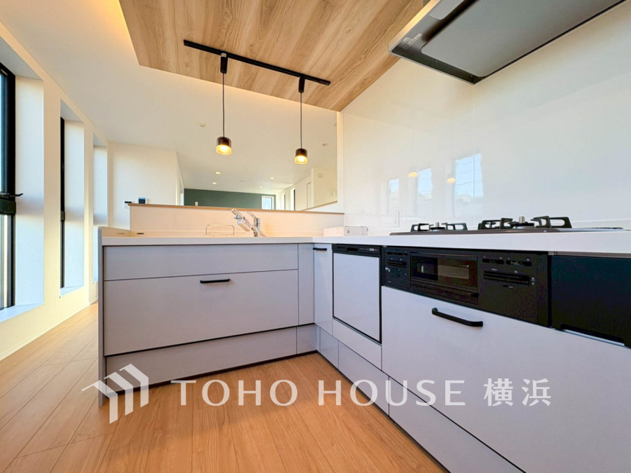 木目天井と間接照明が美しい、機能的で開放感あふれるL字型キッチン空間です。