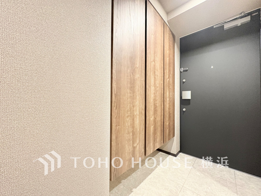 シンプルで清潔感のある玄関。木目調の収納が空間に温かみをプラスします。靴や小物の整理に便利です。