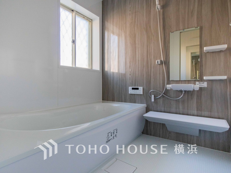 木目調の壁が温かみを演出する、明るく清潔感のあるバスルーム。ゆったりとした浴槽でリラックスできます。