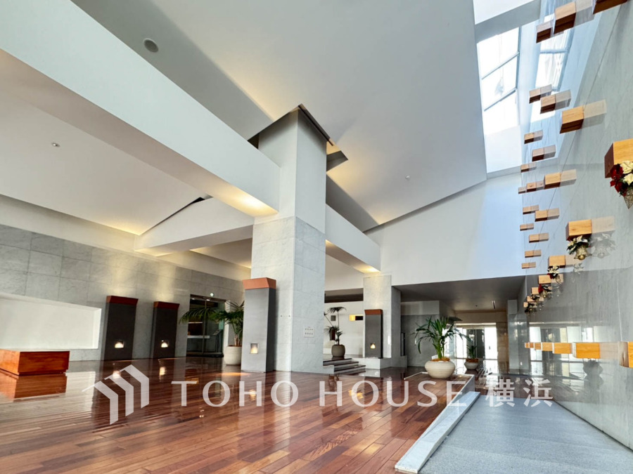 開放感あふれる高い天井と自然光が差し込む、洗練されたデザインのエントランスロビー。