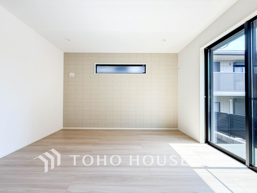 明るい自然光が差し込むリビング。シンプルで落ち着いたアクセントウォールが魅力の空間です。