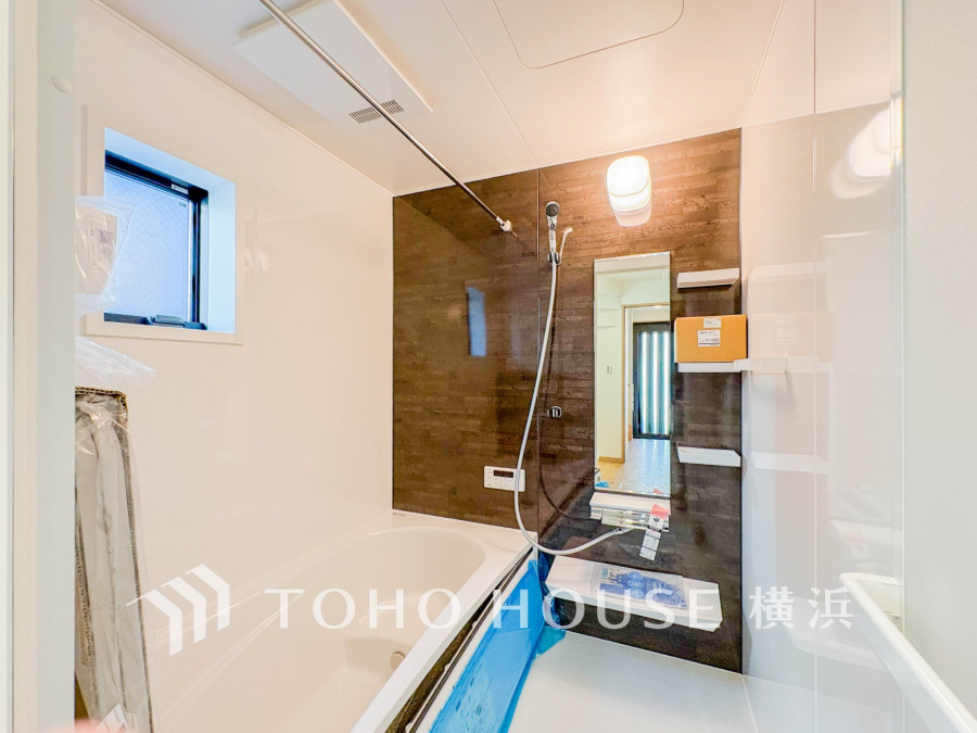 落ち着いたブラウンのアクセントパネルと窓付きで明るい、清潔感あふれるバスルームです。