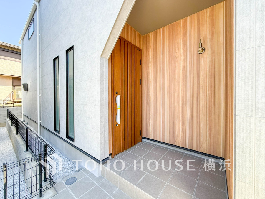 木目調の壁とドアが温かみを演出する、シンプルで清潔感あふれる玄関ポーチです。