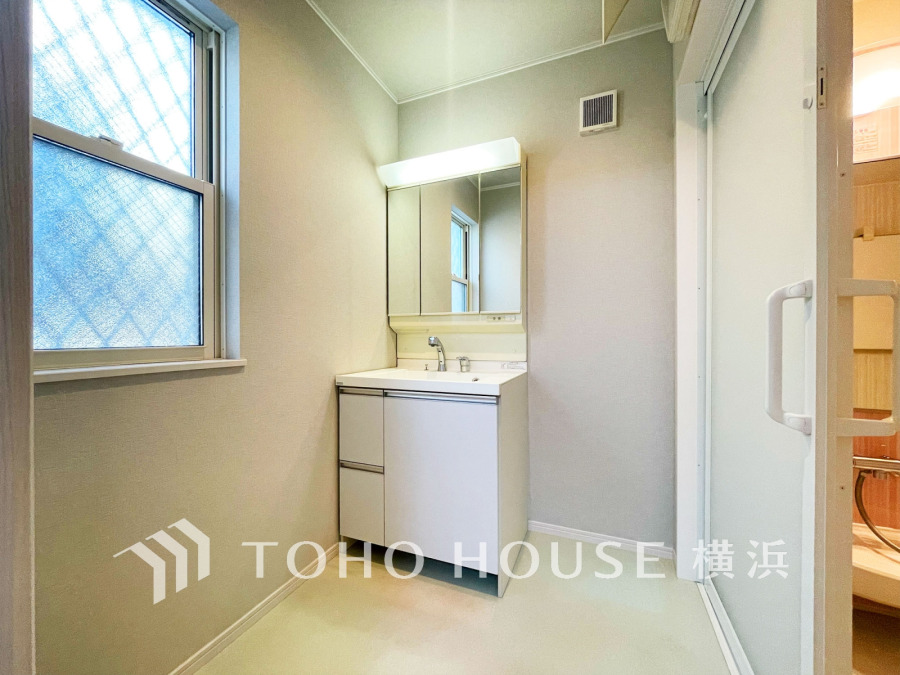 清潔感あふれる洗面スペース。大きな鏡と収納付きで使い勝手も良く、窓から自然光が差し込みます。