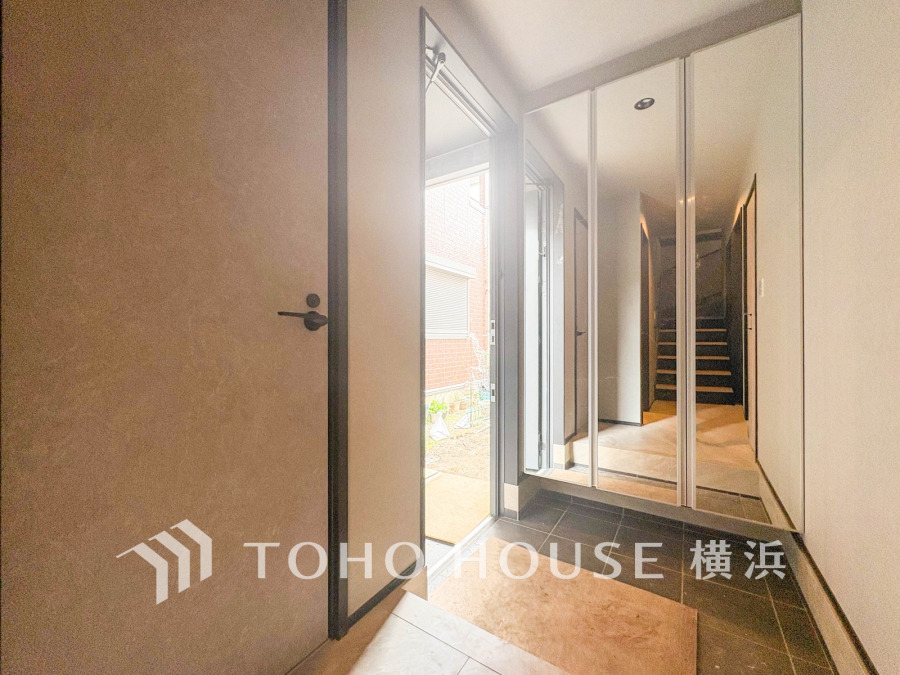 大容量の鏡付き収納が備わった明るい玄関。外からの光が差し込み、開放感あふれる空間です。