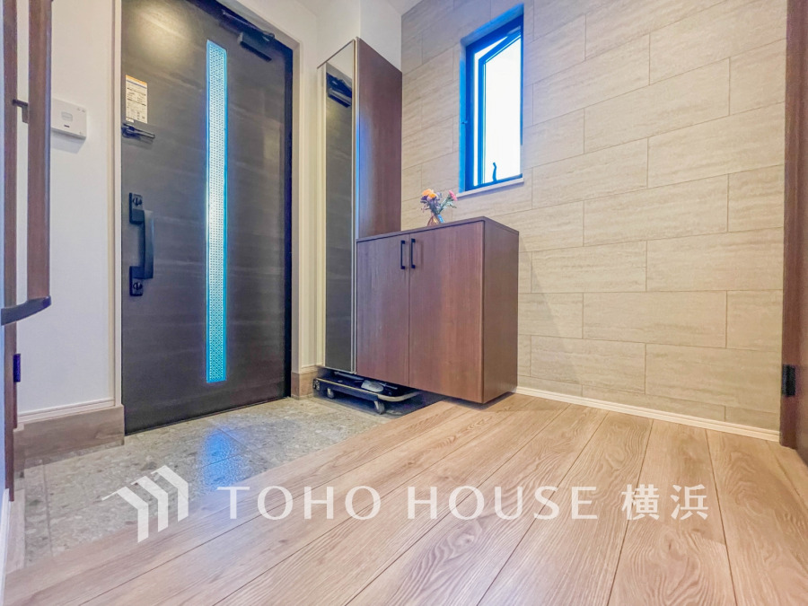 明るい窓から自然光が差し込む、収納力に優れたシンプルで清潔感のある玄関スペースです。