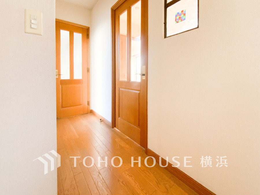 温かみのある木製ドアとナチュラルな木目のフローリングが調和した、明るく清潔感のある廊下空間です。