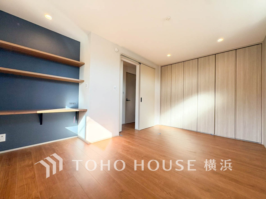 ナチュラルな木目床に落ち着いたネイビー壁面が映える、収納充実の明るい居室空間です。