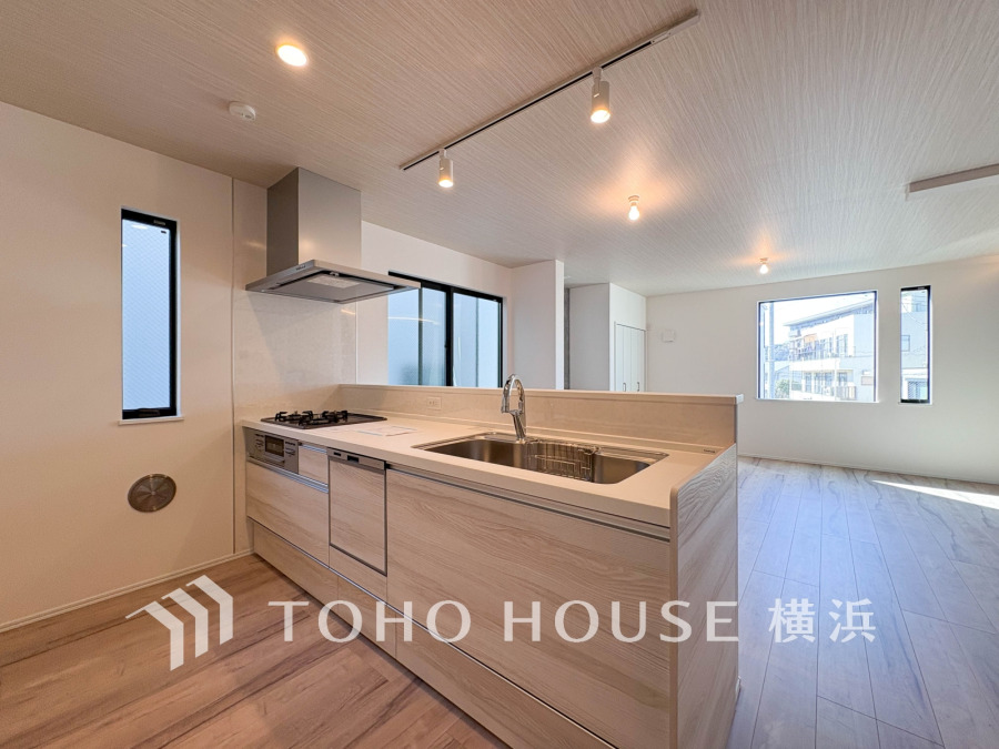 明るい自然光が差し込む、機能的でスタイリッシュなオープンキッチンと広々としたリビング空間。