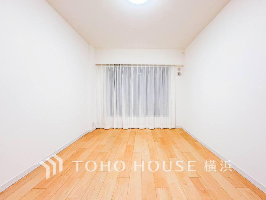明るい光が差し込む、シンプルで清潔感あふれる無垢材フローリングの洋室です。