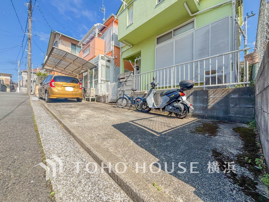 陽当たり良好な駐車スペース付きの住宅外観。バイクや自転車の駐輪も可能な便利なエリアです。