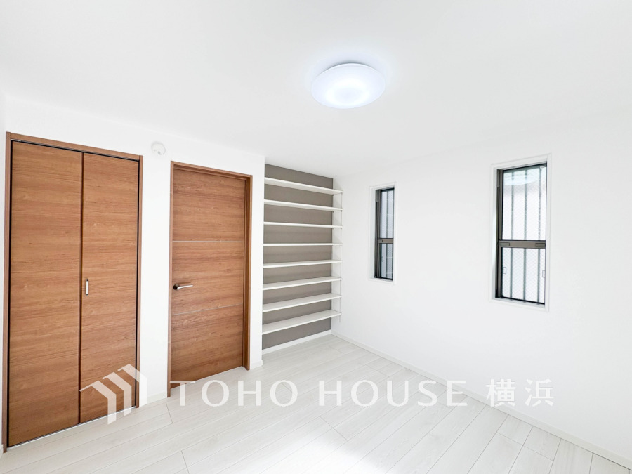 木目調の扉と白を基調とした明るい室内、壁面の収納棚が便利なシンプルで機能的な居室空間です。