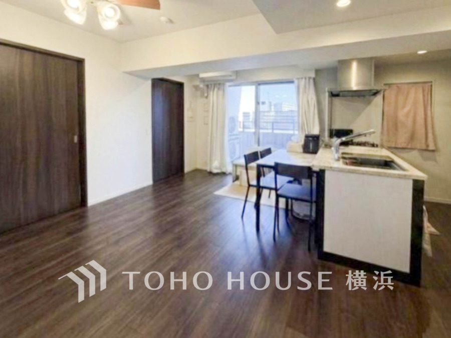 落ち着いた木目調の床と明るい窓辺が調和する、開放的なリビングキッチン空間です。