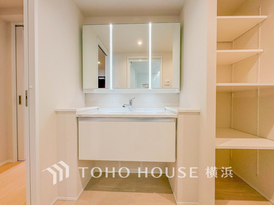 収納棚付きの清潔感ある洗面台。広々とした鏡と照明で快適な身支度をサポートします。