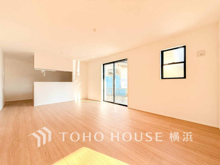 陽光が差し込む広々としたリビング。ナチュラルな木目床と白壁が明るく開放的な空間を演出します。