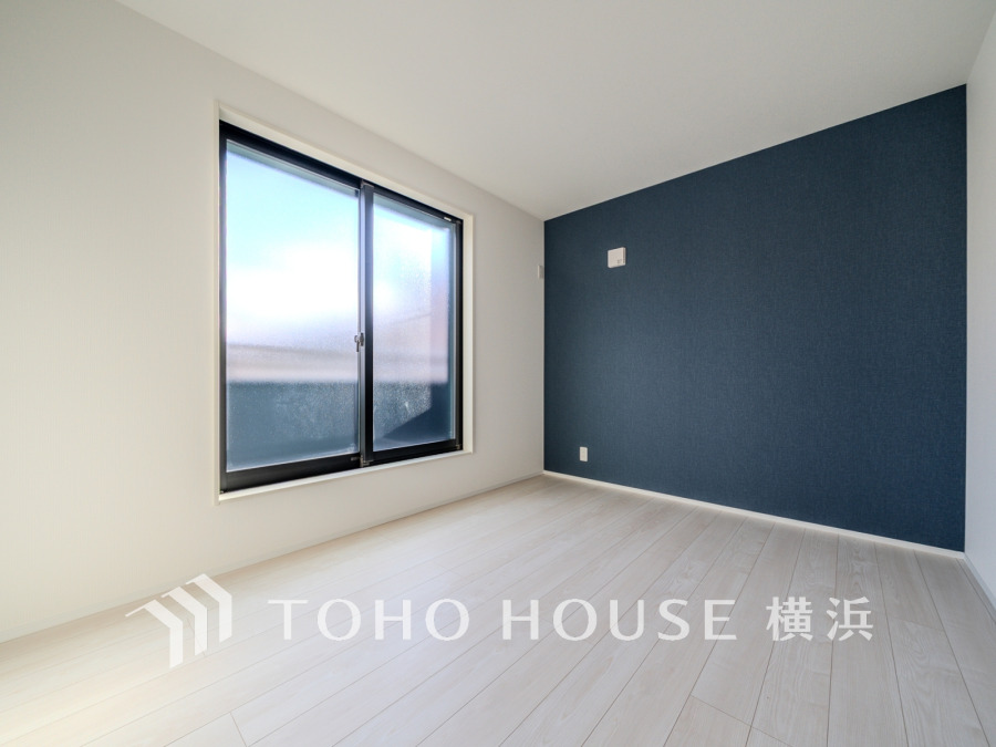 バルコニーから明るい自然光が差し込む洋室。アクセントクロスが演出するスタイリッシュな空間です。