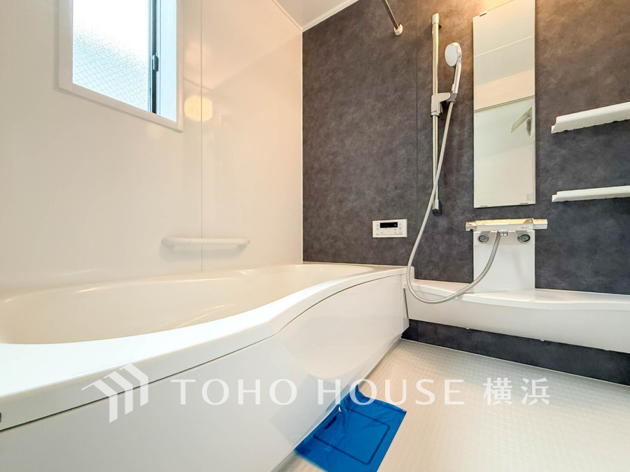 落ち着いたダークカラーの壁と清潔感ある白でまとめた、ゆったり寛げるバスルームです。