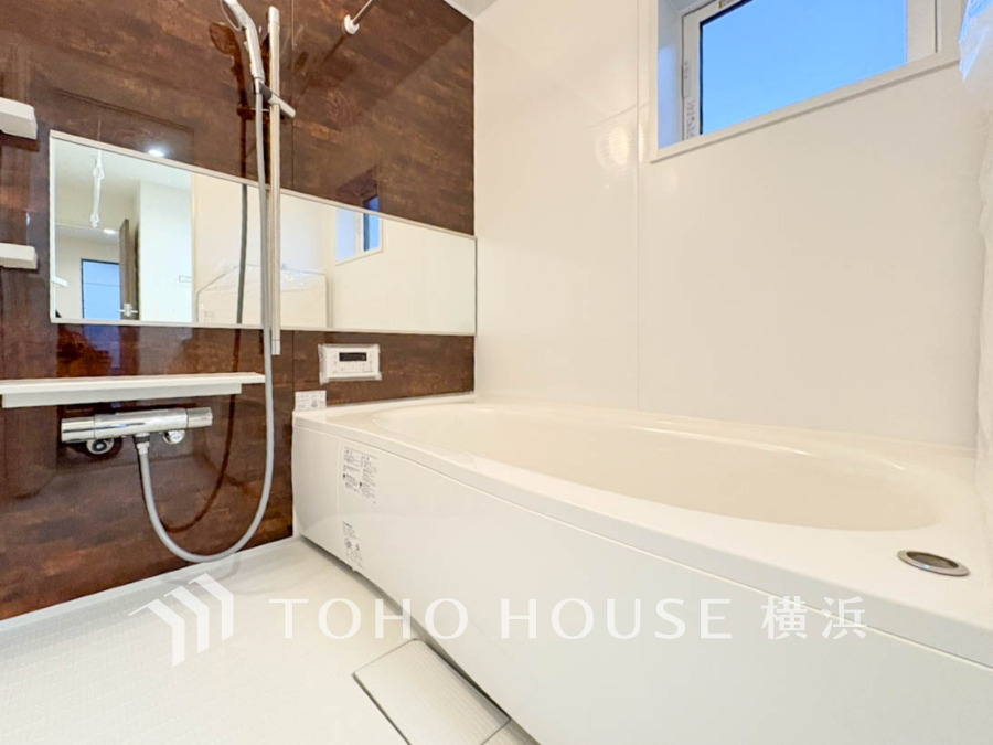 落ち着いた木目調の壁と清潔感あるホワイトを基調とした、ゆったり寛げるバスルームです。窓から自然光も採り入れます。