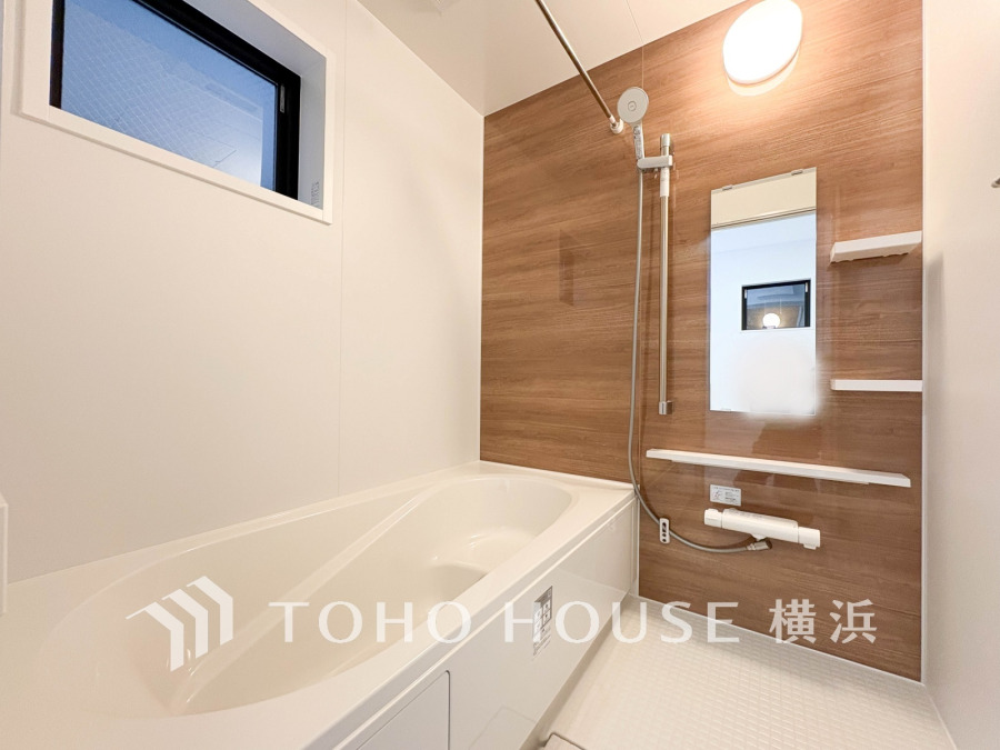 木目調のアクセントパネルが温かみを演出する、清潔感あふれるバスルームです。