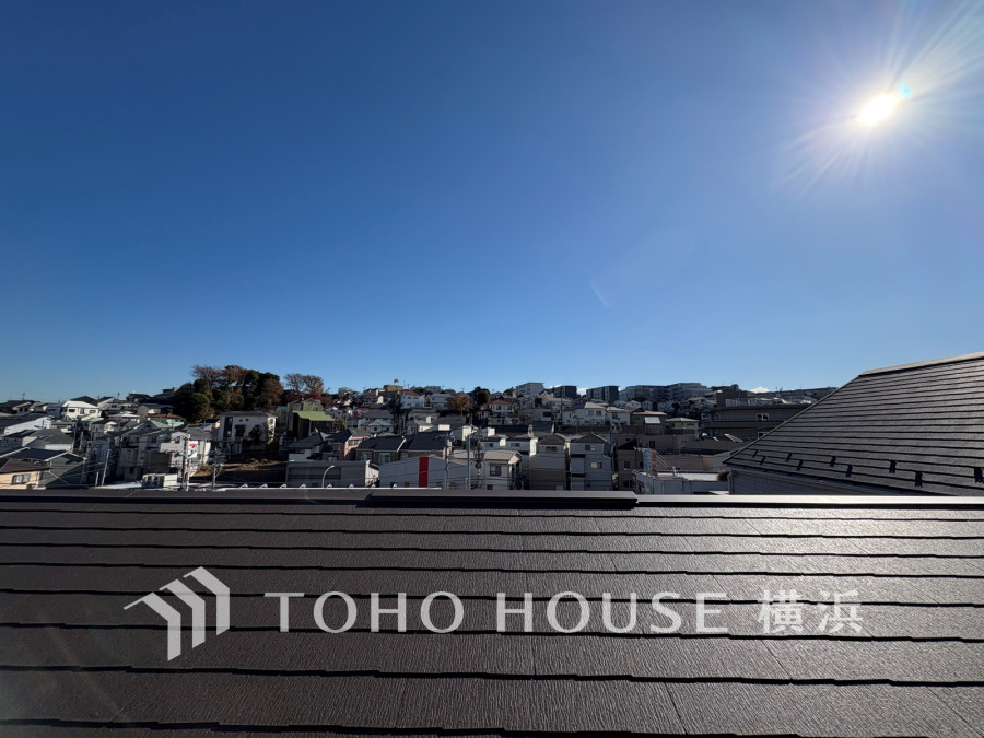 晴天の空の下、見晴らしの良い住宅街が広がるバルコニーからの眺望です。日当たり良好で開放感があります。