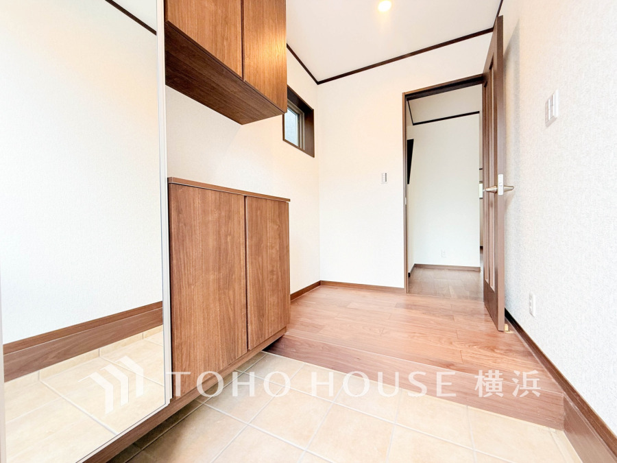 木目調の収納と大きな鏡が設置された明るい玄関スペース。広々としたゆとりある空間が魅力です。