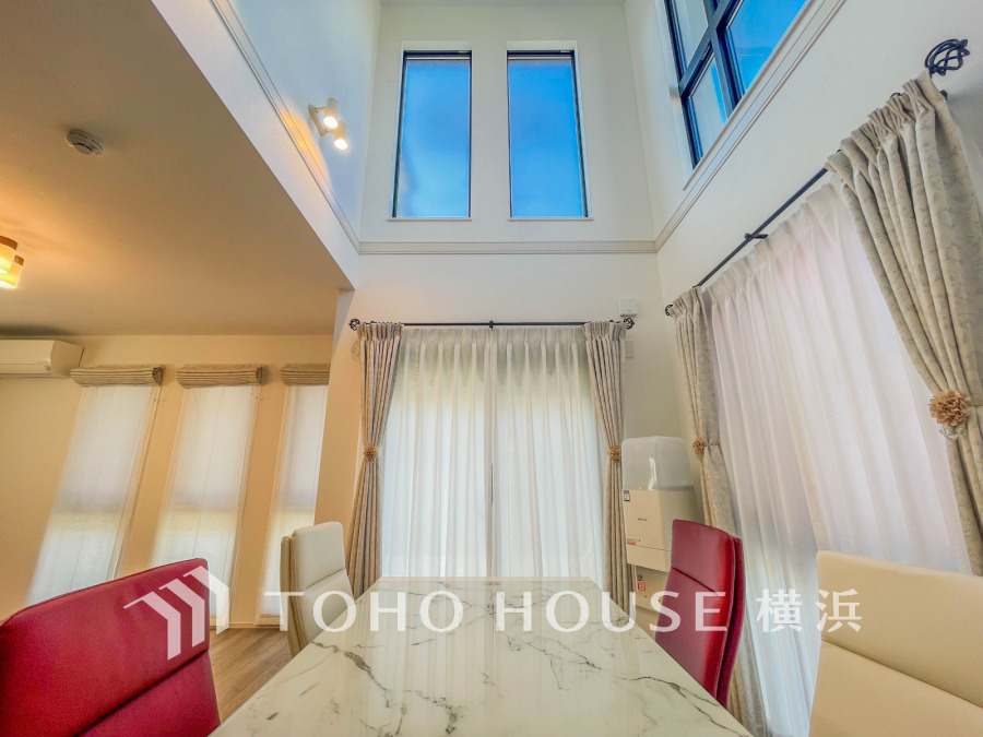 縦の空間を活かし、床面積以上の開放感と採光をもたらすダイナミックなリビング。高い窓から明るい光が差し込み、光と風が通り抜ける快適な空間を演出しています。