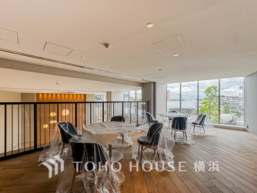 大きな窓から自然光が差し込む開放的な共有スペース。木目調フロアで温かみのある落ち着いた空間です。