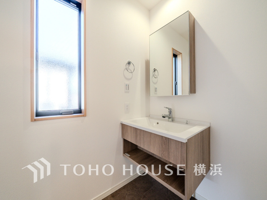 ナチュラルウッド調の洗面台と大きな鏡が備わった、明るく清潔感のある洗面スペースです。