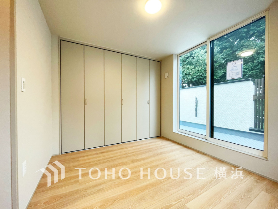 大きな窓から自然光が差し込む明るい洋室。壁一面の収納でお部屋をすっきり保てます。