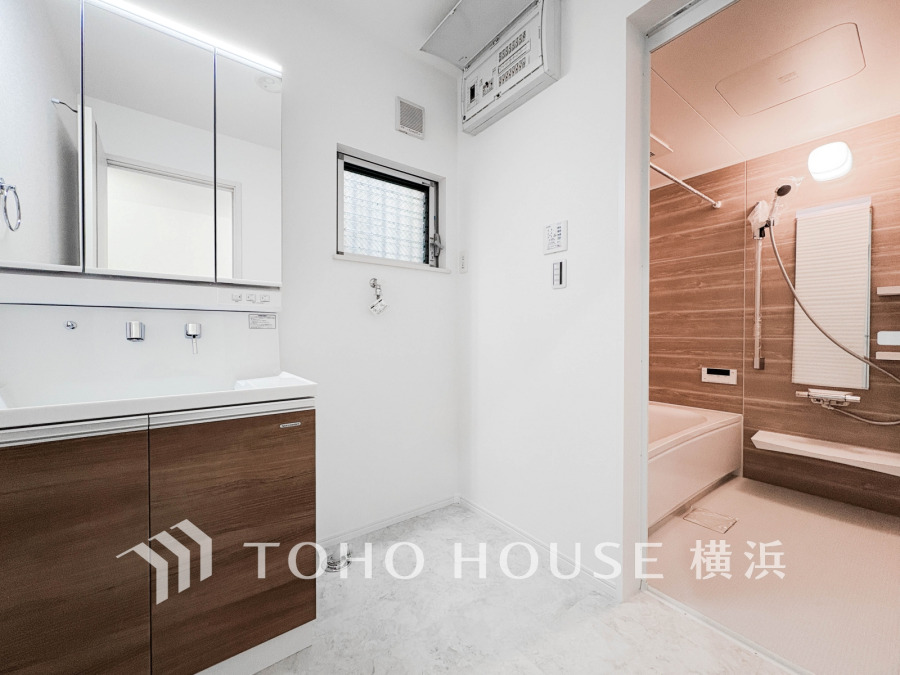 清潔感あふれる洗面脱衣所。木目調の収納と温かみのある浴室で快適なバスタイムを実現します。