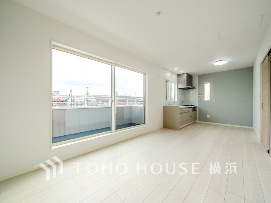 大きな窓から自然光がたっぷり入るリビング。清潔感のあるキッチンと調和した快適な空間です。