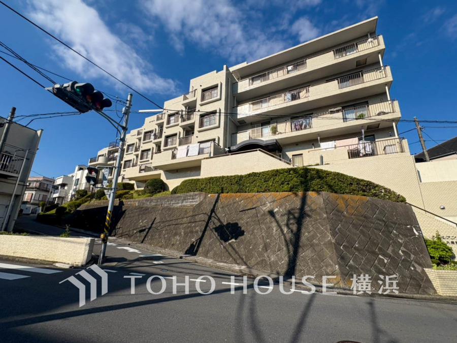 陽当たり良好な高台に立つ、安心感のある重厚なタイル貼りマンションの外観です。