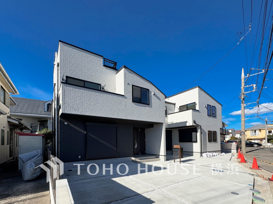 洗練されたデザインの１号棟が、青空の下で輝きます。これから創り上げる庭や駐車場で、家族の夢が広がりますね。