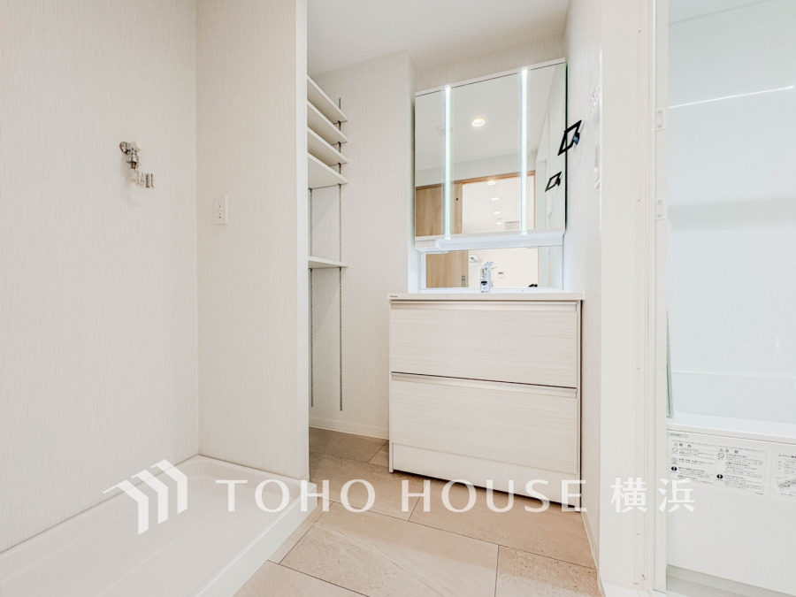 清潔感あふれる洗面スペース。収納棚付きで使いやすく、隣接の洗濯機置き場も便利な設計です。