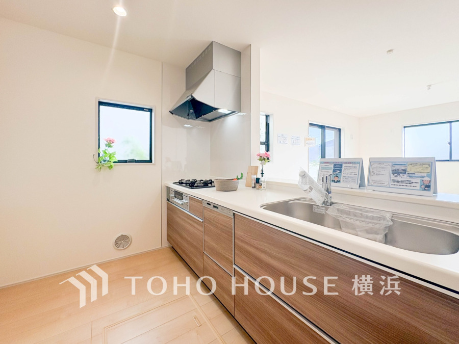 木目調の収納が美しい、明るく開放的な対面キッチン。家族との会話も楽しめる快適な空間です。