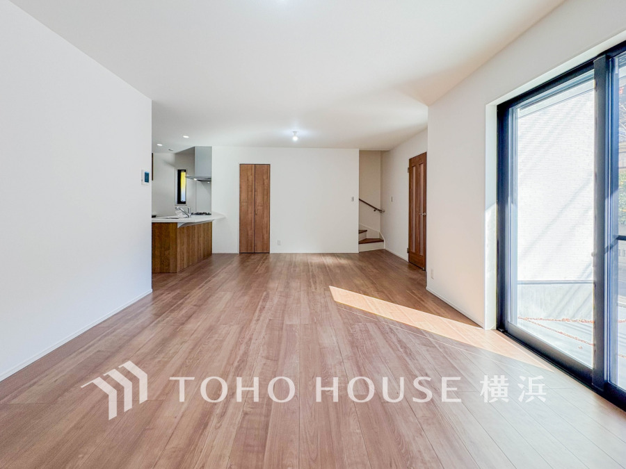 大きな窓から光が差し込む、明るく開放的なリビングダイニング。木目調の床が温かみを演出します。