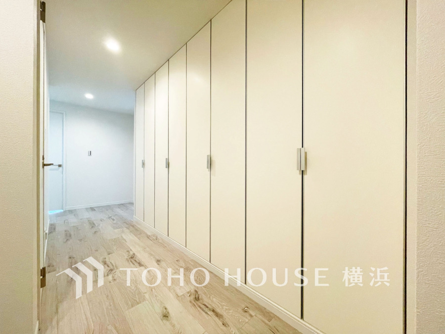 壁一面に設置された大容量収納で、すっきりとした空間を実現。明るく清潔感のある廊下です。