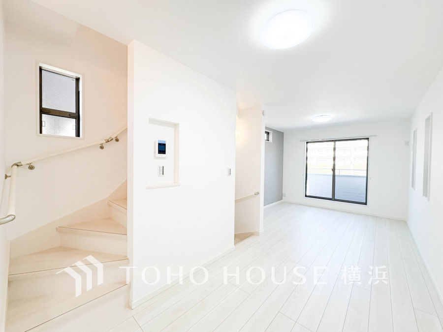 明るい自然光が差し込む、清潔感あふれるホワイト基調のリビング空間。階段と一体化した開放的な設計です。