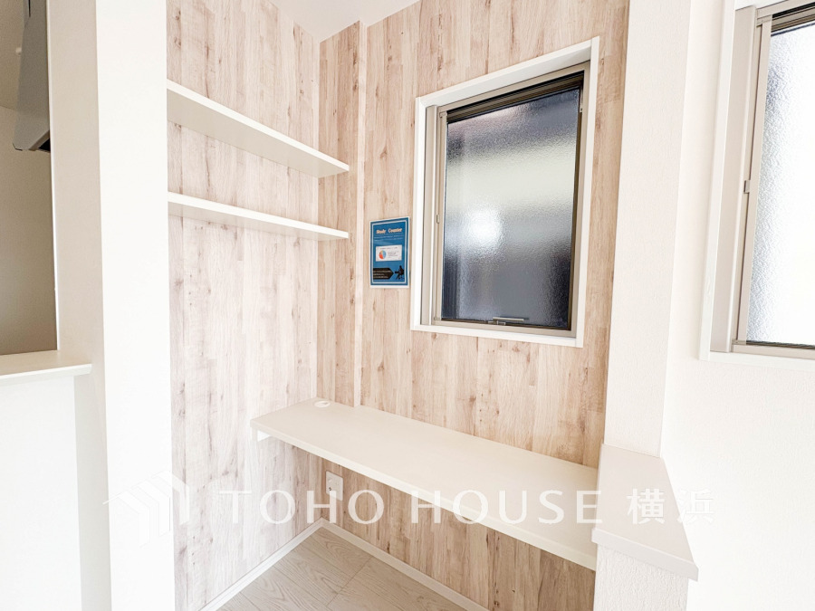 木目調の壁が温かみを演出する、窓付きの明るいワークスペース。収納棚も備えた機能的なデスクコーナーです。